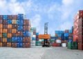Colorful shipping containers and forklift in a busy Jakarta port under blue skies.